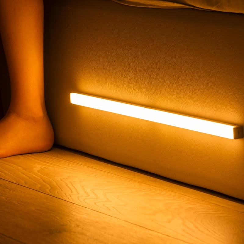 Under-cabinet LED sensor light bar glowing under a kitchen shelf