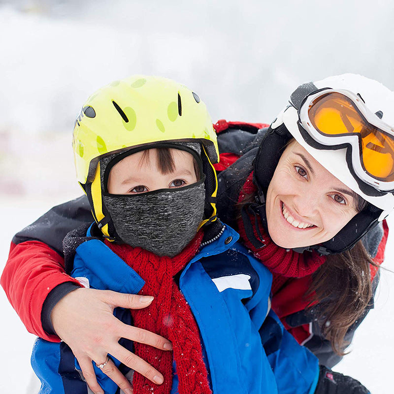 Child wearing a gray balaclava under a helmet on the slopes