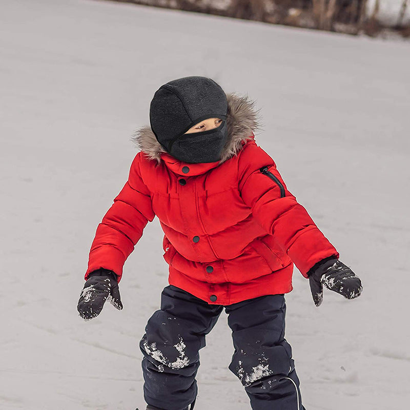 Child in red jacket wearing a black balaclava hood in the snow