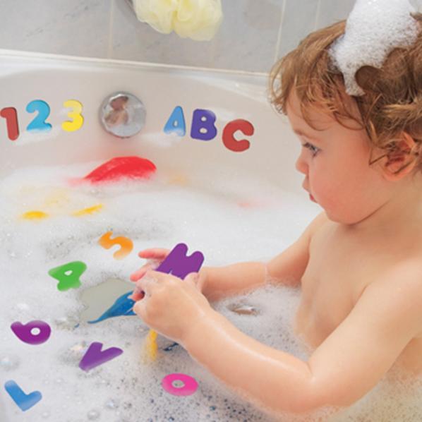 Child playing with bath letters and numbers in the tub