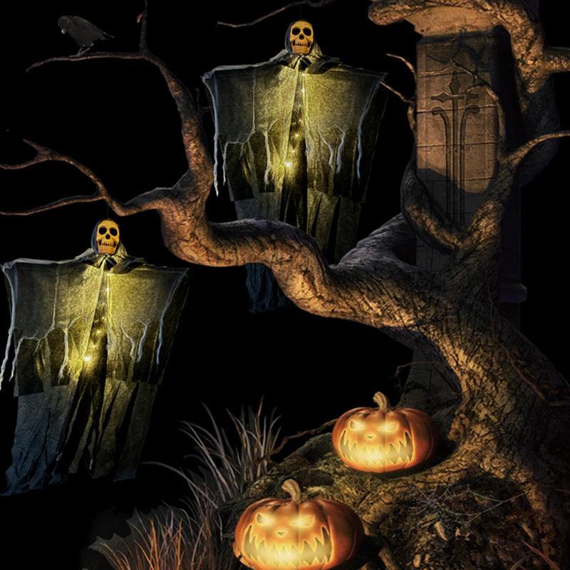 Two glowing warm LED hanging ghosts in a tree at night with pumpkins