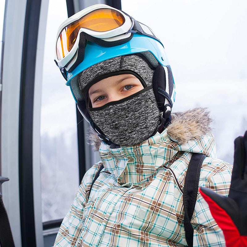 Child wearing a gray balaclava face and neck warmer under a ski helmet