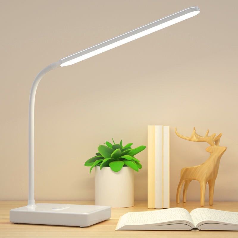 White rechargeable LED desk lamp on a desk with books