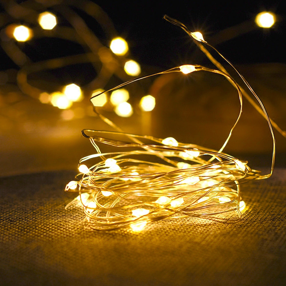 Copper wire fairy string lights glowing warm white around a glass jar