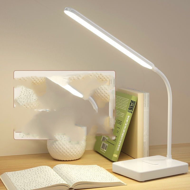Folding LED desk lamp lighting an open book